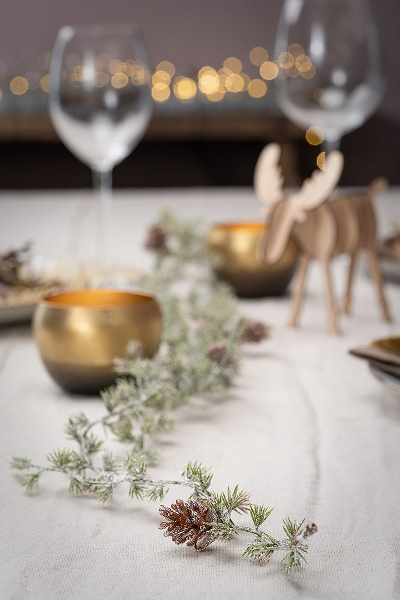 Küsntliche Girlande Lärchenbaum mit Zapfen auf dem Tisch dekoriert